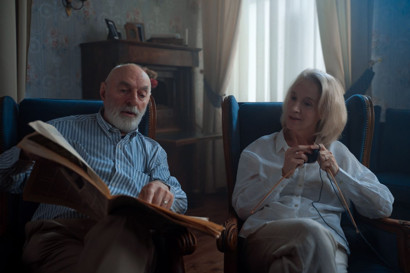 Casal de idosos lendo e tricotando em casa
